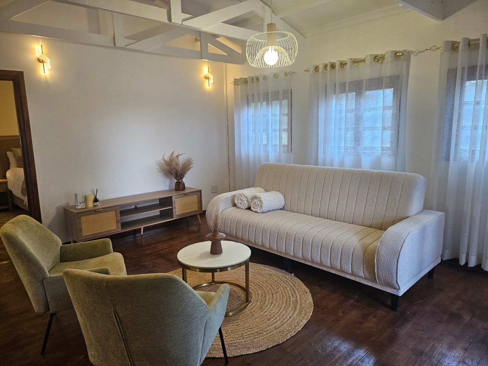 Bridal suite lounge with a boucle sofa, armchairs and a view through to the bedroom